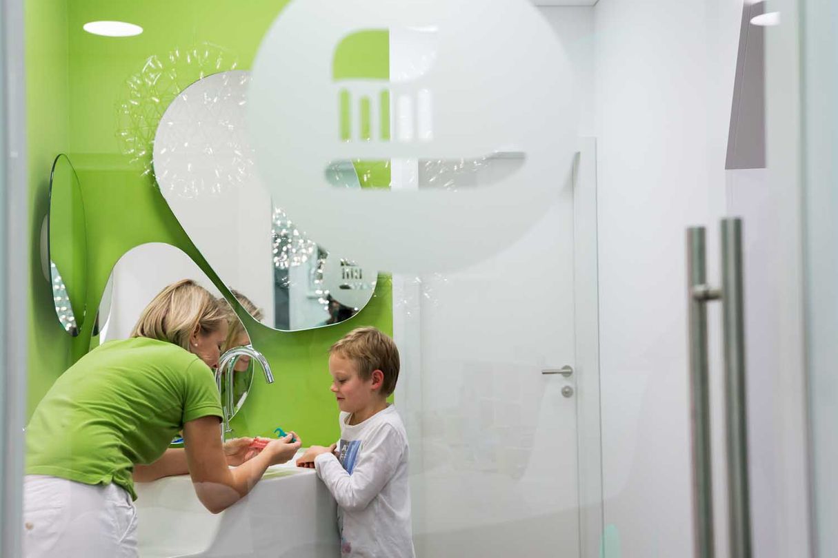 Mitarbeiterin zeigt einem Jungen das richtige Zähneputzen